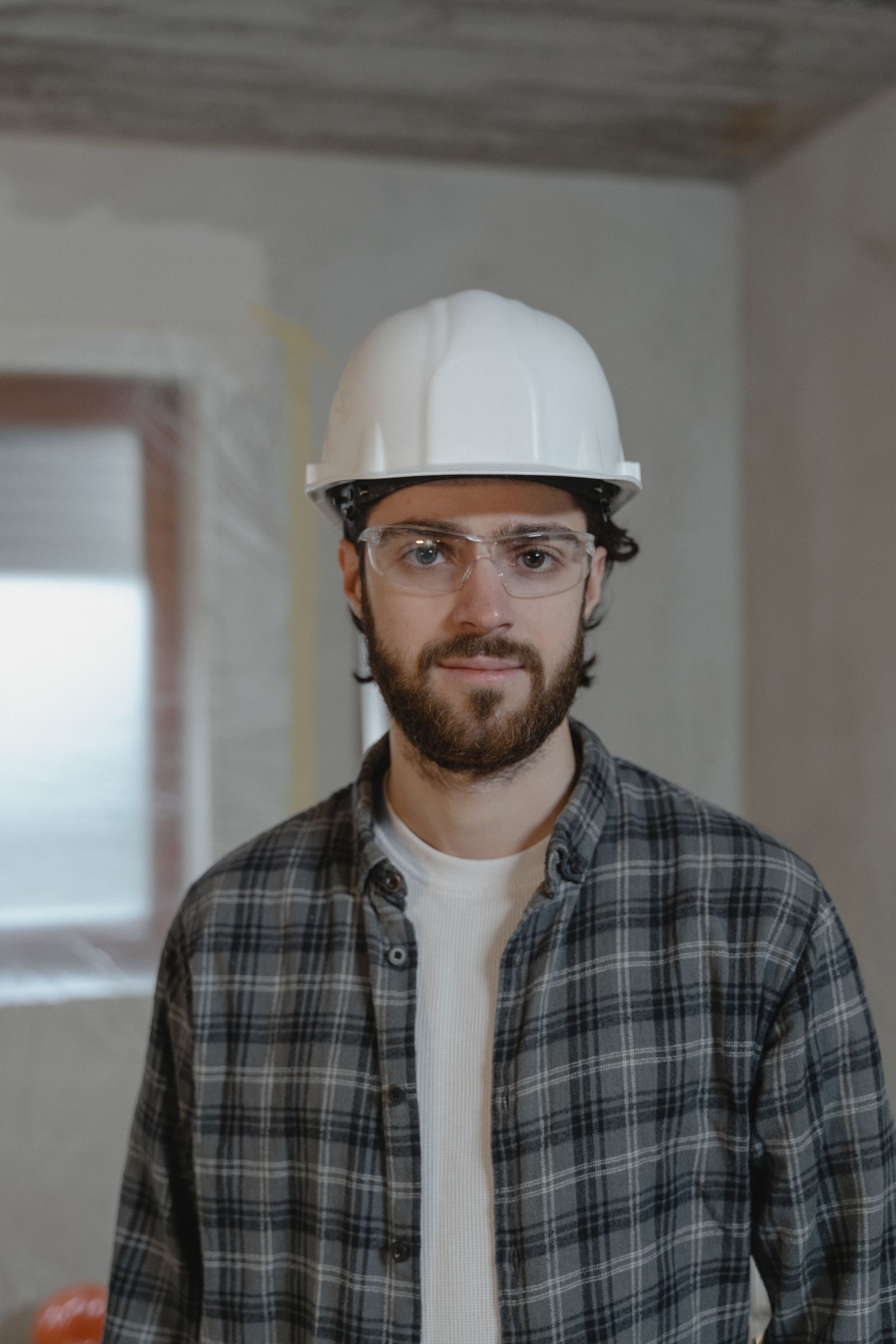 Tradie in a hard hat standing against a brick wall
