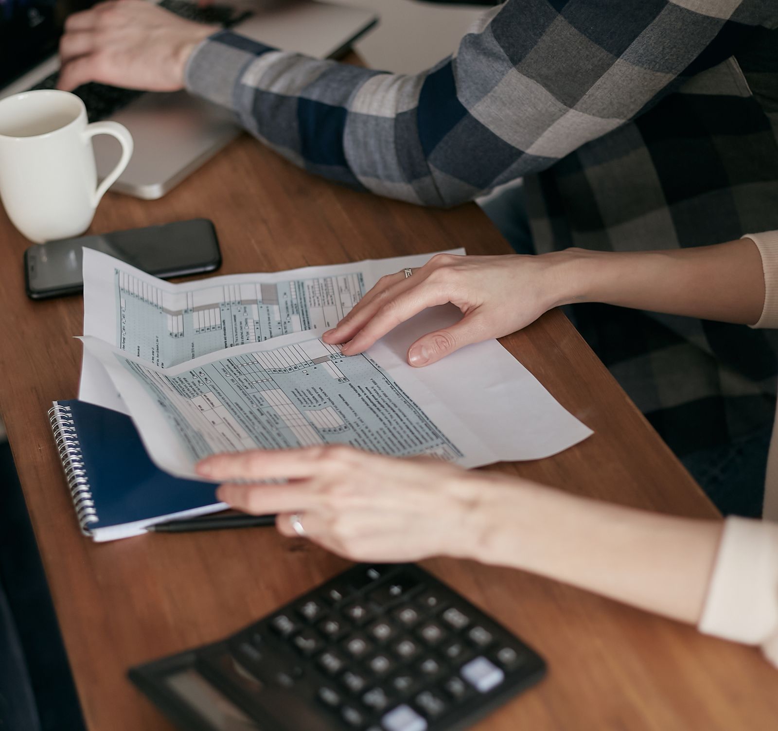 Hands holding tax forms on a wooden table