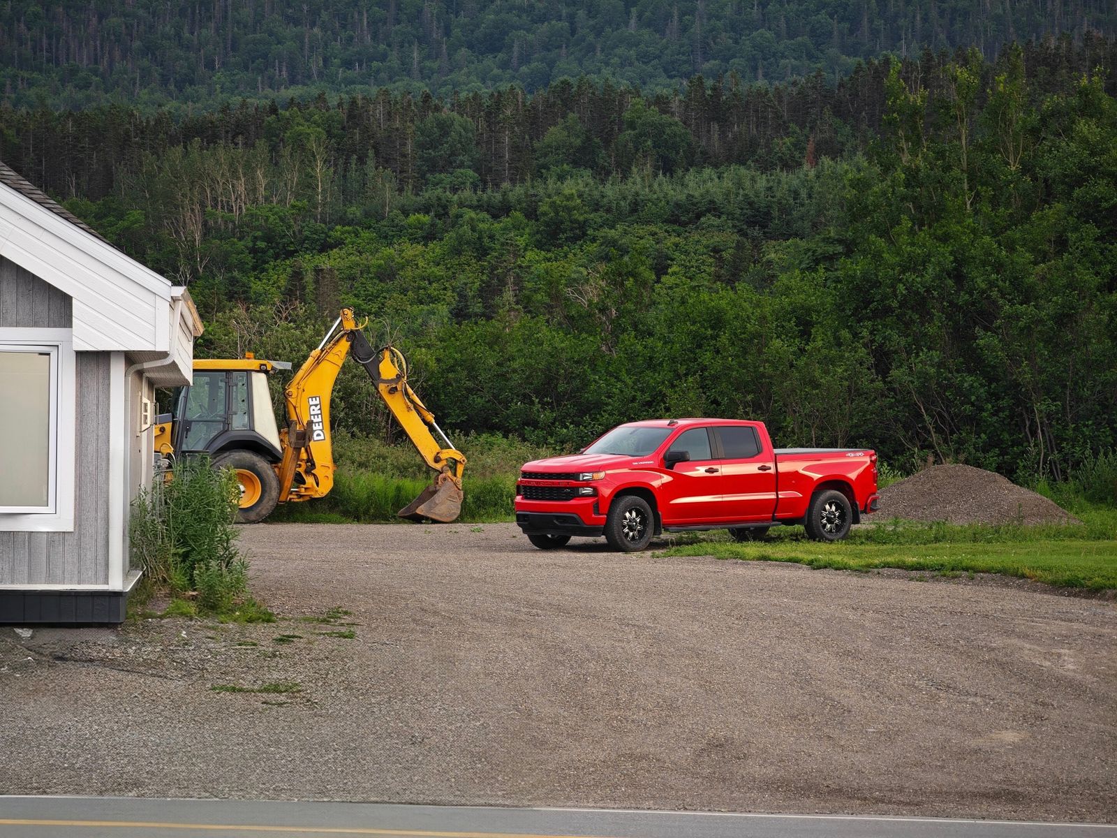 Work ute parked next to a backhoe on a rural worksite